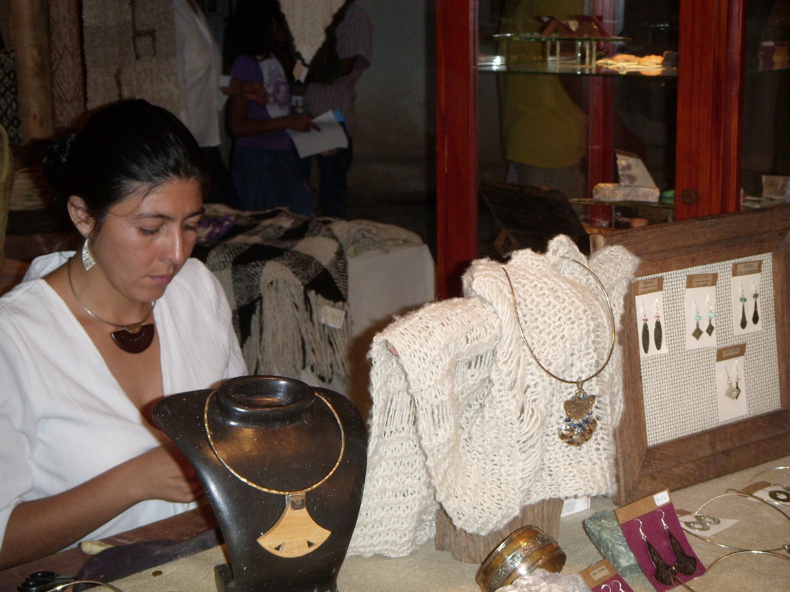 Artesana y piezas textiles exhibidas en la feria artesanal.
